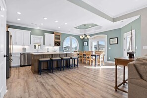 A spacious kitchen with a central island, bar stools, and a dining area with a view. - All the Views by Brunswick Vacation Rentals: w/ Heated Pool & Views, Near beach (Ocean Isle Beach)