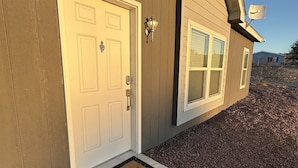 A house with two doors, a satellite dish, and a welcome mat.