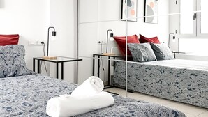 A modern hotel room with two beds, a small table, and a bedside table with a lamp. - Adela Homes by Best Holidays Fuerteventura (Corralejo)