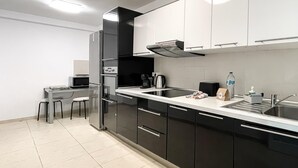 A modern kitchen with black cabinets, a stainless steel sink, and a built-in microwave. - Adela Homes by Best Holidays Fuerteventura (Corralejo)
