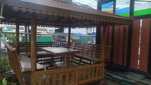 Ein hölzerner Gazebo mit einer Bank und einem Tisch, umgeben von einem dekorativen Geländer.