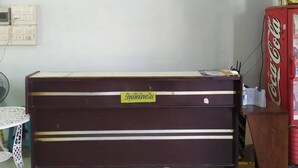 Ein Zimmer mit Holzschrank, Ablagefläche mit Dekoration, Ventilator und einem Coca-Cola-Kühlschrank.