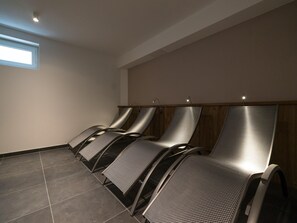 A row of massage chairs in a room with a sloped ceiling and a small window.