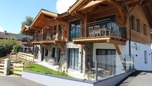A modern hotel with wooden balconies, stone facade, and outdoor seating area. - Penthouse near Kaprun with sauna & stunning views (Piesendorf)