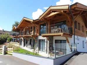A modern hotel with wooden balconies, stone facade, and outdoor seating area. - Penthouse near Kaprun with sauna & stunning views (Piesendorf)