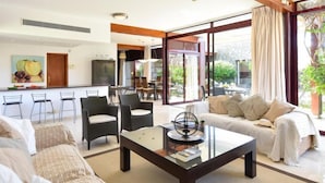 A spacious living area with a sofa, chairs, a coffee table, and a dining area with a glass door leading outside. - Villa Tauro 2 by Interhome (Mogan)