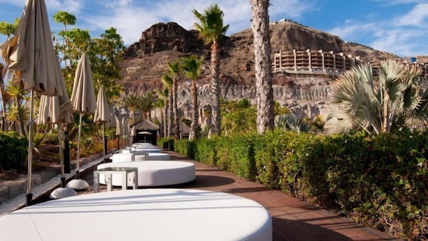 A resort with outdoor seating areas, palm trees, and a mountainous backdrop. - Villa Tauro 2 by Interhome (Mogan)