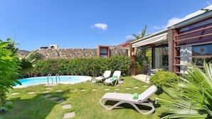 A backyard with a swimming pool, lounge chairs, and a stone wall. - Villa Tauro 2 by Interhome (Mogan)