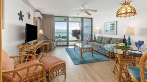A spacious living room with a television, comfortable seating, a dining area, and a balcony with a view of the sea. - Whale Watching from your lanai, unbeatable views (Lahaina)