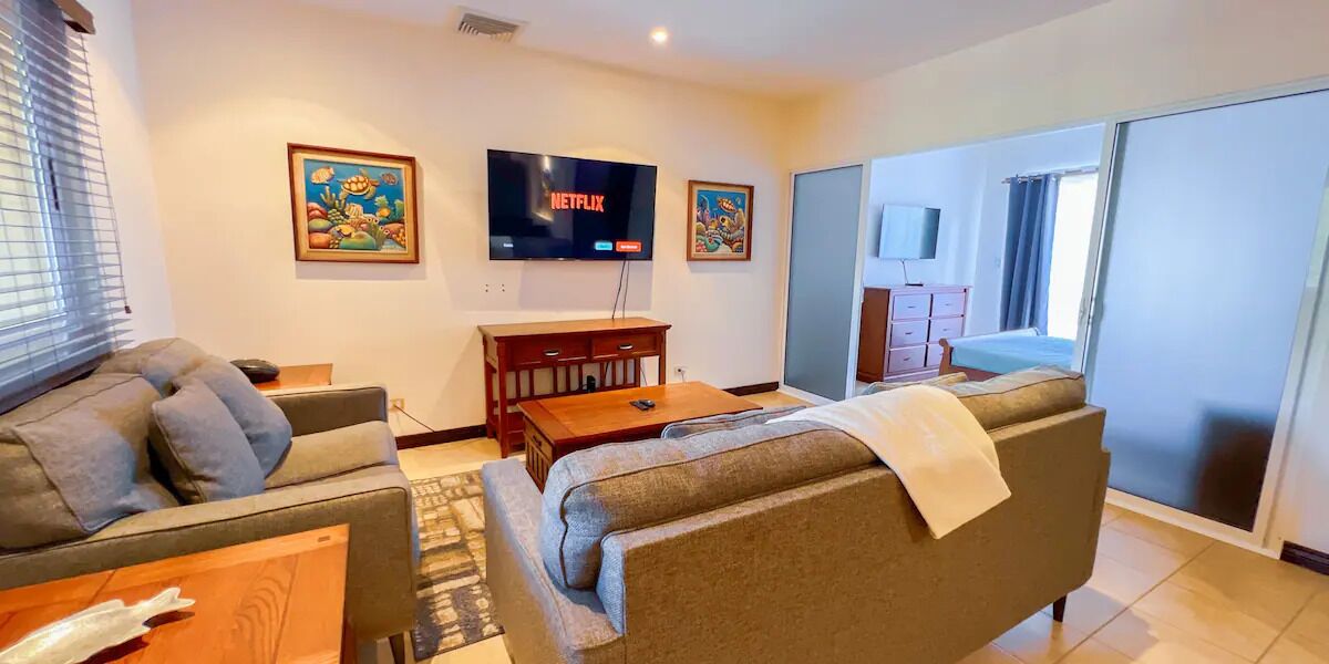 A modern living room with a sofa, a coffee table, and a flat-screen TV mounted on the wall.