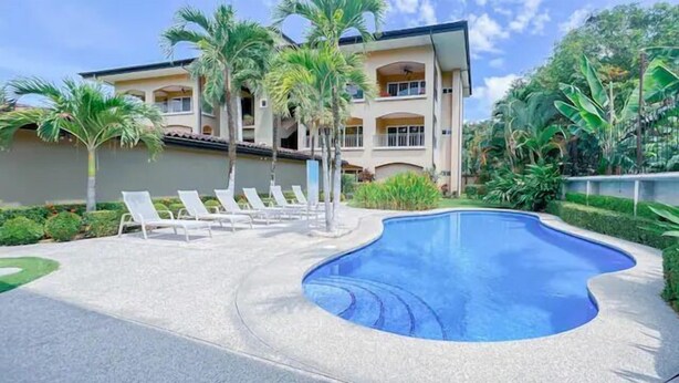 Um hotel com piscina, palmeiras e um jardim bem cuidado.