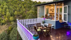 Una terraza con mesa y sillas, con vista a un paisaje boscoso.