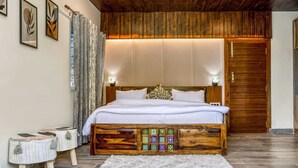 Un dormitorio con techo de madera, una cama grande con cabecera decorativa, dos mesitas de noche y un armario de madera.