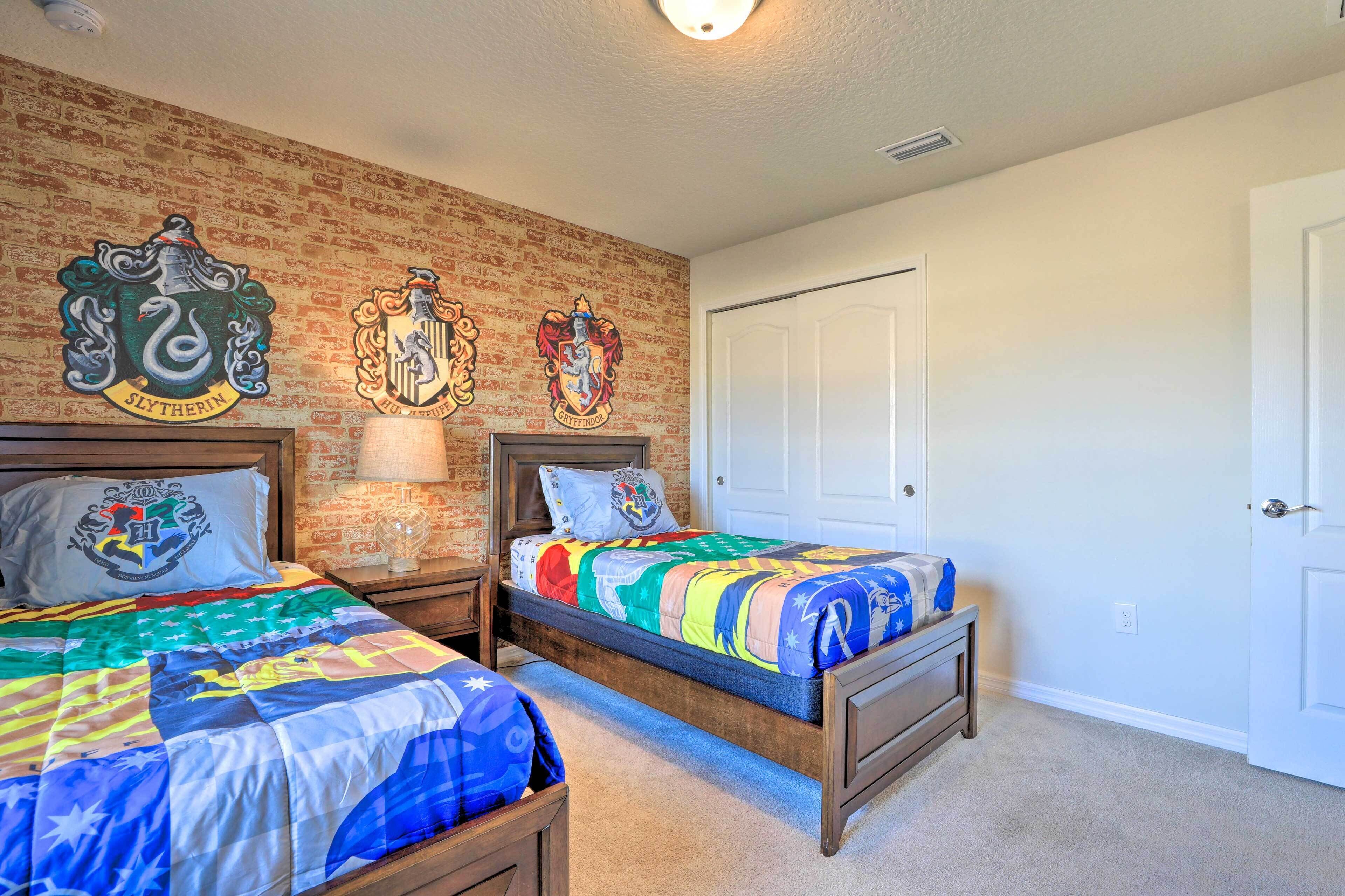 A bedroom with two beds, each with a Gryffindor crest, a brick-patterned wall, and a white door.