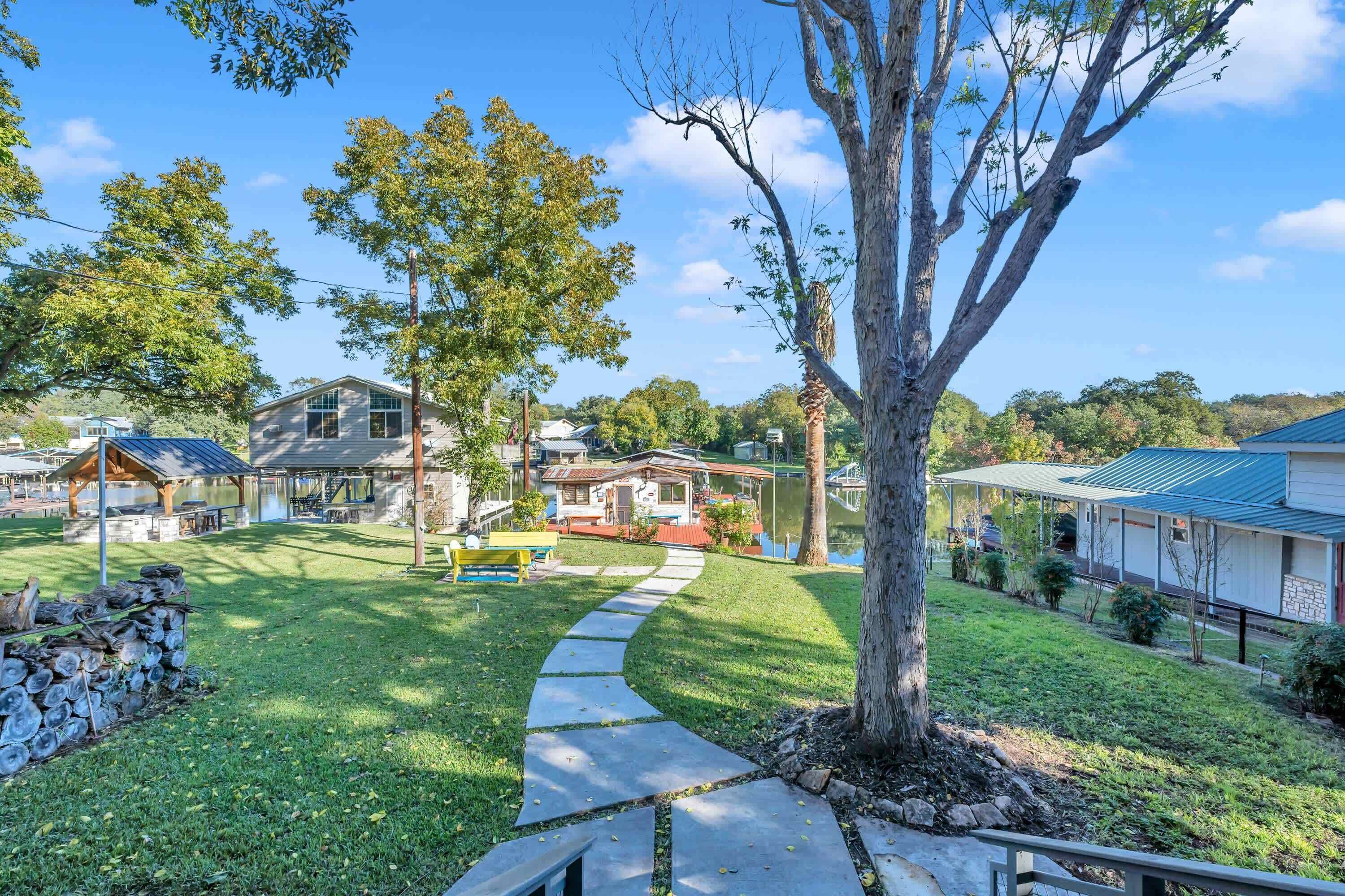 A residential area with a paved pathway, a wooden bench, and a large tree.