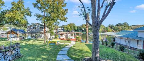 A residential area with a paved pathway, a wooden bench, and a large tree.