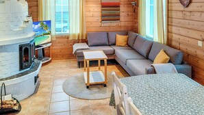 A cozy cabin interior with a fireplace, wooden walls, a sofa, and a dining table.