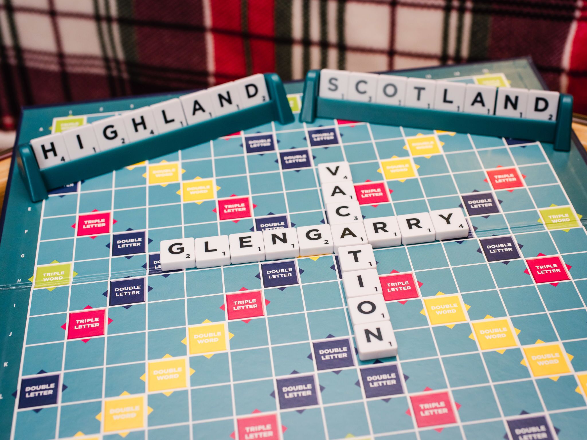 A Scrabble board with the words "HIGHLAND," "SCOTLAND," "VACATION," and "GLENGAT" spelled out.