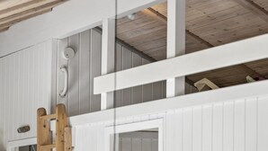 Een kamer met een entresol, houten balken en een witte deur.