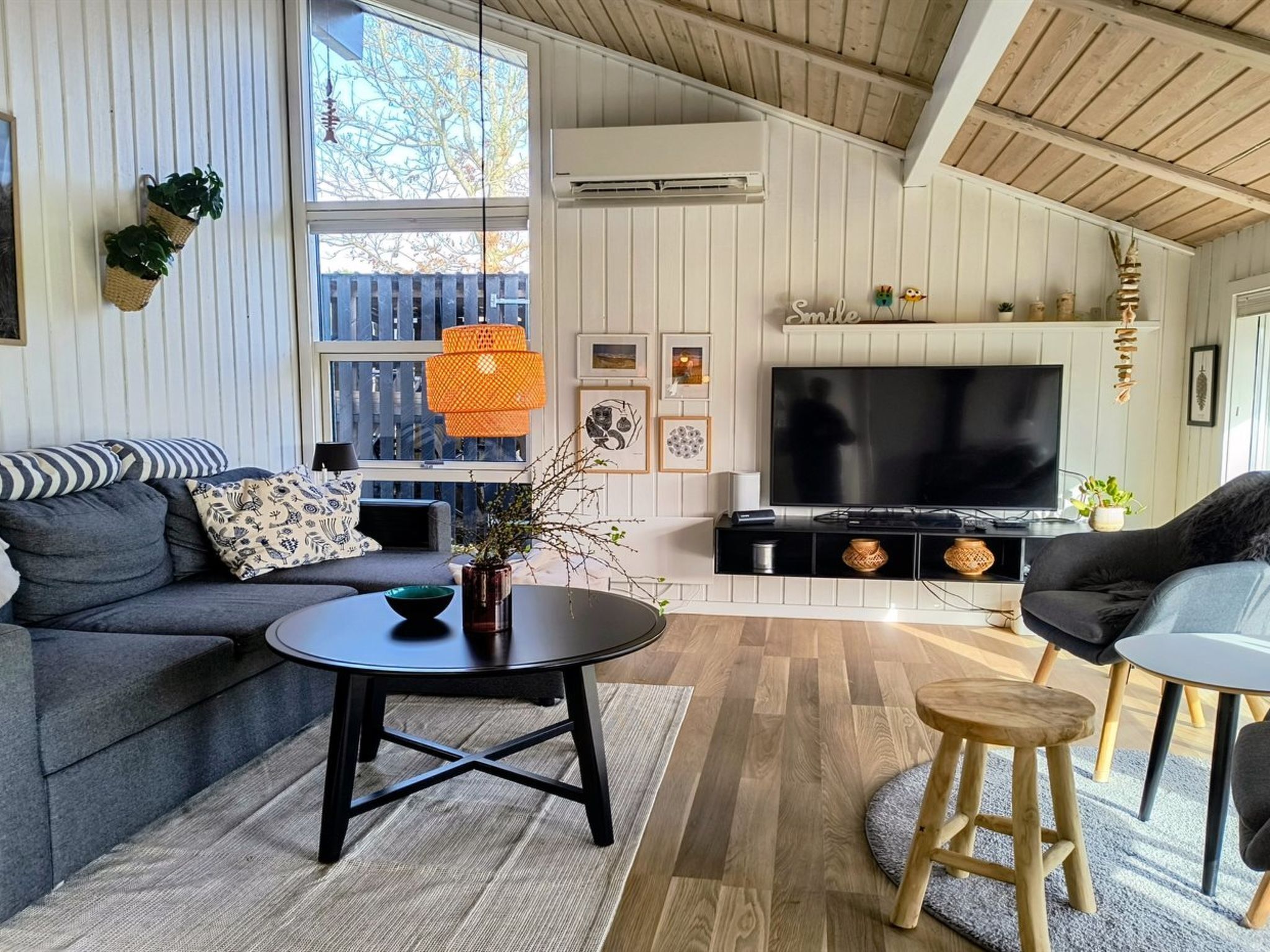 A living room with a sofa, a coffee table, a TV, and a wooden ceiling.