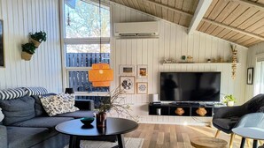 Een woonkamer met een bank, een salontafel, een televisie en een houten plafond.