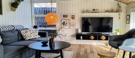 A living room with a sofa, a coffee table, a TV, and a wooden ceiling.