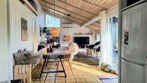 Een ruime keuken met een houten plafond, een eethoek met een tafel en stoelen, en een groot raam dat zorgt voor daglicht.