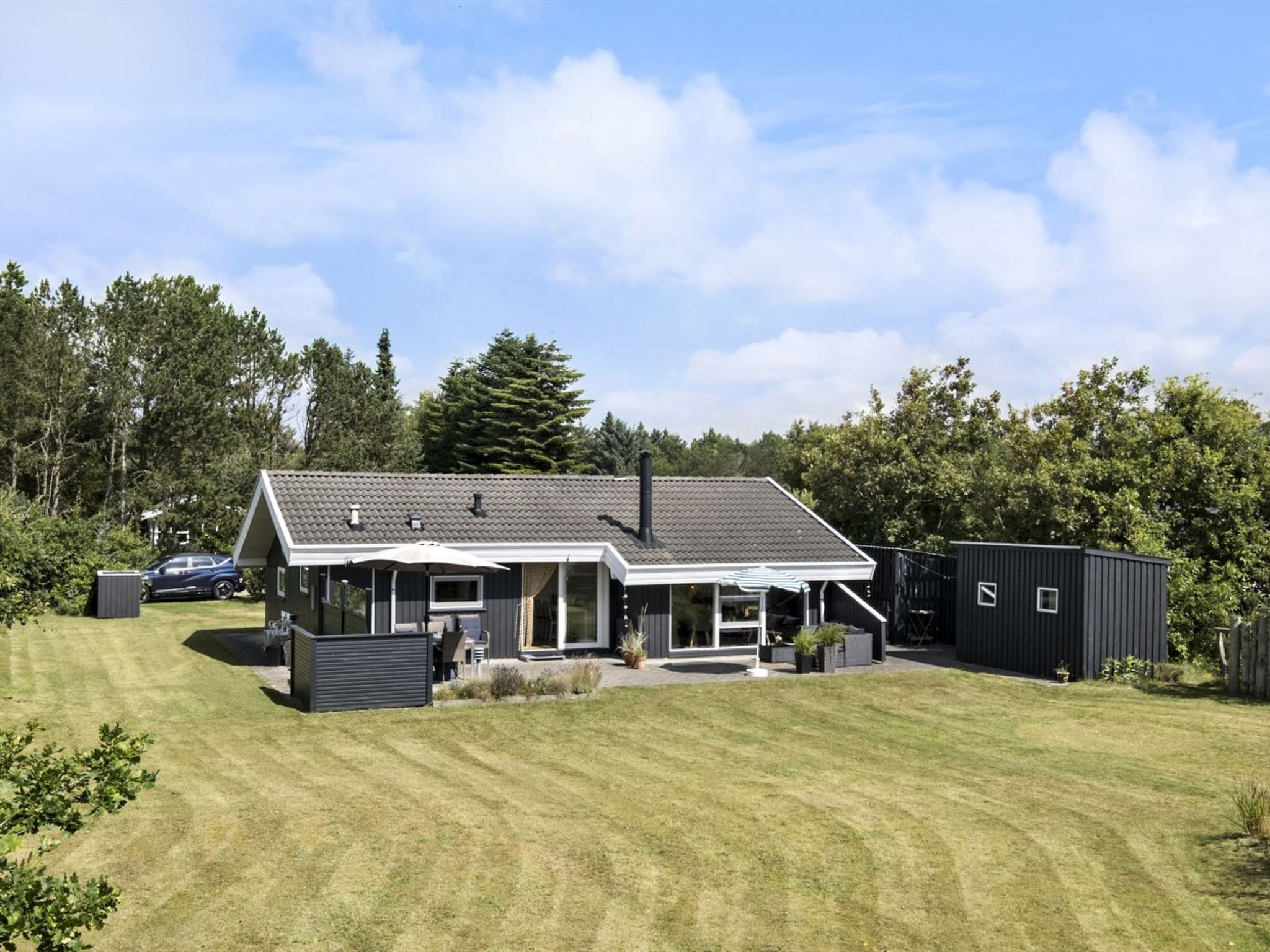 A modern house with a covered patio, a garage, and a well-maintained lawn.