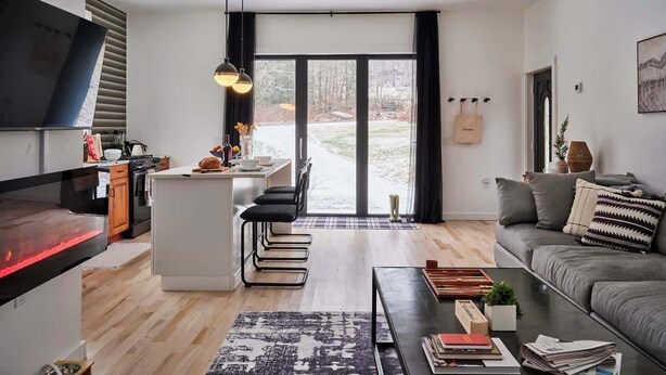 A modern living room with a sofa, coffee table, and a kitchen area with a central island.