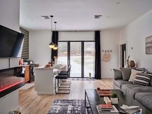 Un salon moderne comprenant un canapé, une table basse et un coin cuisine avec un îlot central.