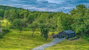 A secluded cabin surrounded by lush greenery and a forested hill.