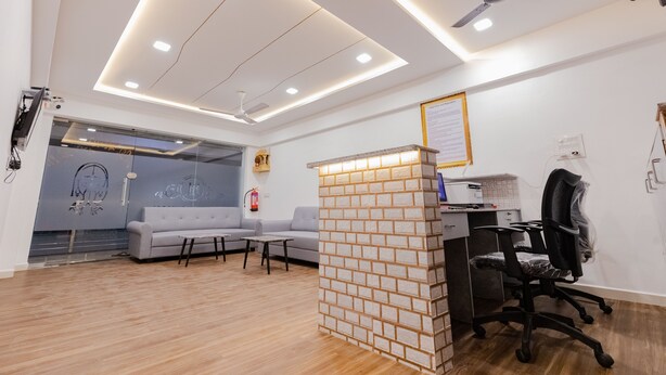 A modern office space with a reception desk, a grey sofa, and a black office chair. - Hotel Lennox Best In surat (Surat)