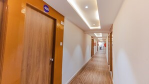 A hotel corridor with wooden doors, a number sign, and recessed lighting. - Hotel Lennox Best In surat (Surat)