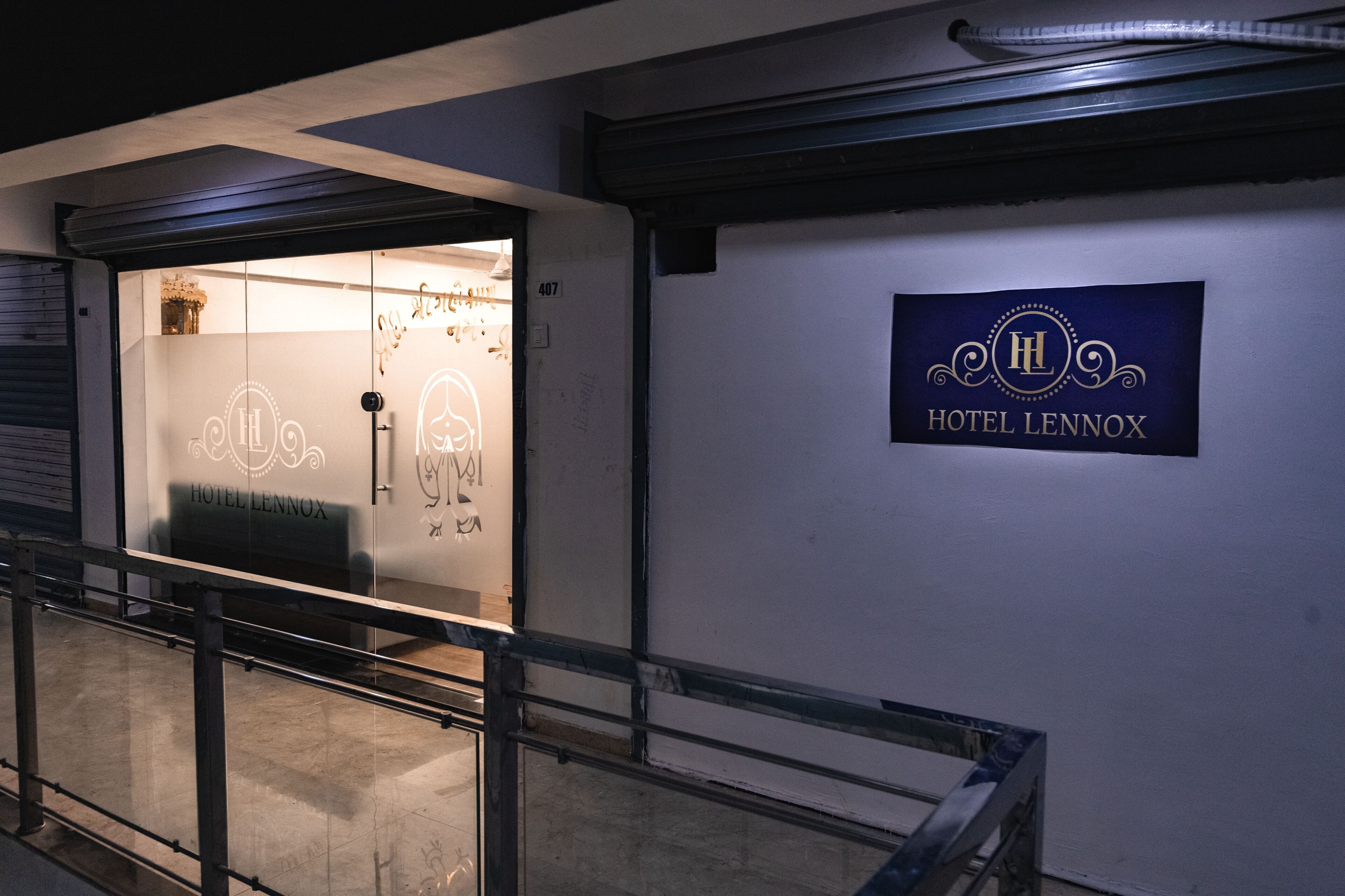 A hotel entrance with a glass door, a sign reading "Hotel Lennox," and a metal railing in the foreground.