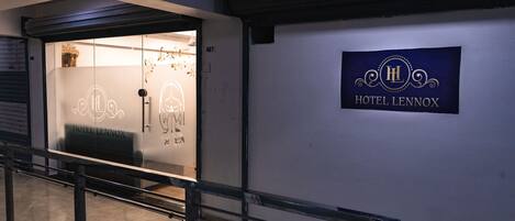 A hotel entrance with a glass door, a sign reading "Hotel Lennox," and a metal railing in the foreground.