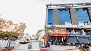 A hotel with a modern facade, a sign for Hotel Lennox, and several shops including a restaurant and a bank. - Hotel Lennox Best In surat (Surat)