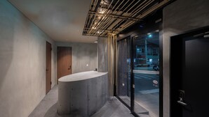 A modern bathroom with a large, curved sink, a glass door leading outside, and visible pipes on the ceiling. - BESTIE - DOYANEN HOTELS (Osaka)