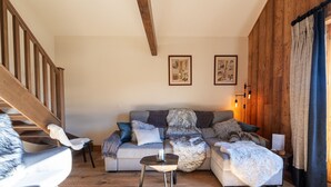 Una sala de estar acogedora con una escalera de madera, un sofá gris y una mesita auxiliar pequeña.