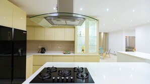 Een moderne keuken met een centraal kookeiland, een rvs afzuigkap en een eethoek met een stoel en tafel.