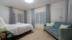 Een hotelkamer met een bed, een bank, een deur en gordijnen.
