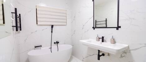 A modern bathroom with a freestanding bathtub, a sink with a mirror, and a towel rack.