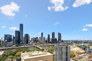 A cityscape with modern skyscrapers, a river, and a bridge. - Chic 2-Bed with Rooftop Overlooking the City (South Brisbane)