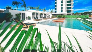 Et moderne hotel med poolområde, liggestole og palmer.