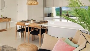 Una sala moderna con sofá, reposapiés y comedor.