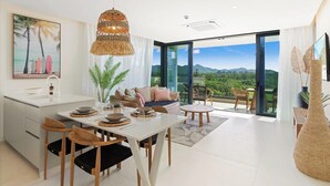 Un espacio habitable moderno con comedor, cocina y un balcón con vistas a la montaña.