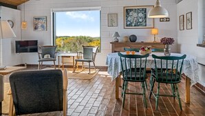 A cozy dining area with a wooden ceiling, a large window offering a view of the outdoors, and a table set with chairs and a vase of flowers. - "Ehawee" - 350m from the sea by Interhome (Saltum)