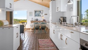 A modern kitchen with white cabinetry, a wooden ceiling, and a view of the outdoors. - "Ehawee" - 350m from the sea by Interhome (Saltum)
