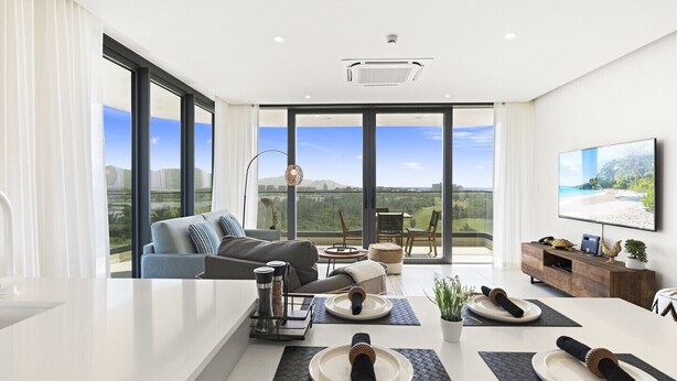 Una sala de estar moderna con una gran mesa de comedor, un sofá y un balcón con vistas al paisaje.