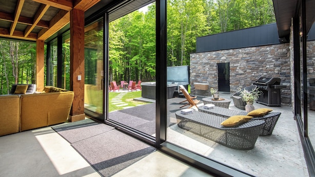 Un espacio exterior moderno con muro de piedra, una parrilla y mobiliario exterior.