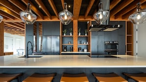 Una cocina moderna con una isla central, taburetes de bar e iluminación colgante.
